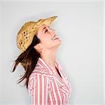 Profile of young Caucasian woman wearing cowboy hat smiling with wind blowing hair.