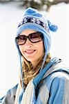 Portrait of attractive smiling mid adult Caucasian blond woman wearing blue ski cap and sunglasses looking at viewer.