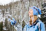 Attractive smiling mid adult Caucasian blond woman wearing blue ski clothing smiling and pointing.