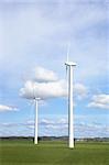 Windmill on a flat landsacpe capturing engergy against a blue sky