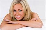 A studio shot of a beautiful young woman laying on her bed