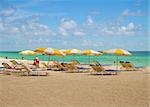 Beach lounge chairs under the shade of colorful umbrellas