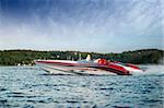 A very large speedboat crusing on a lake.