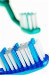 Closeup of two toothbrushes: the first one in focus, the other one out of focus, isolated against white