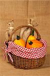 A yellow pumpkins and sacs in the basket, over burlap background. Shallow DOF