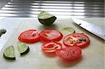 Sliced tomatoes and limes used in asian cuisine with knife on chopping board