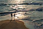 Aerial view of couple holding hands on beach in Bald Head Island, North Carolina at sunset.