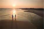 Aerial view of romantic couple standing on beach holding hands on Bald Head Island, North Carolina.