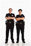 Portrait of two mid adult Caucasian policewomen standing with arms crossed looking at viewer smiling.