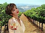 Beautiful woman offering a glass of white wine at vineyard