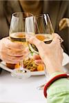 Caucasian mature couple toasting with white wine in restaurant.