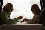 Caucasian mature couple at nice restaurant drinking wine and talking and laughing.
