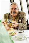 Mature Caucasian couple having dinner in nice restaurant as man gives gift to woman.