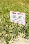 Sign warning visitors not to walk on or disturb natural dune area.