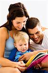 Caucasian parents and toddler son reading book.