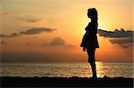 Pregnant woman standing on the beach at sunset