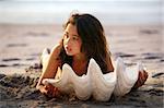 Girl lying behind a seashell at sunset