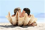 Romantic couple on the beach kissing behind the seashell