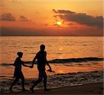 Couple walking on the beach at sunset with some motion blur