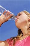 Young girl drinking water out of a plastic bottle outside