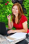 Happy mature woman working on a portable computer in her garden