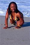 African-American female crawling on beach form sea direction