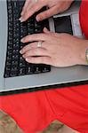 Close up of a female in red dress typing on a laptop