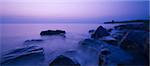 Fantastic scene of coast rocks in sea waves at sunset