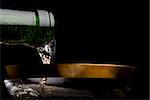 Pouring champagne in a beautiful gold edged glass. black background.