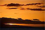 Orange sunset behind island in Pacific ocean.