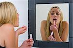 A beautiful young blonde woman putting on her make-up and getting ready to go out