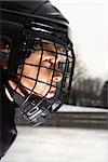 Ice hockey player boy in uniform and cage helmet concentrating.