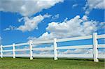 White fence against a bright sky with clouds
