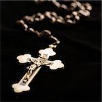 Christian rosary beads with crucifix on black background.