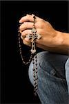 Woman's hands holding rosary with crucifix.