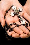 Woman's hands palm up cradling rosary with crucifix.