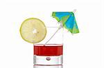 A glass of red juice with a lemon slice and umbrella, reflected on white background