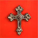 Ornate religious cross hanging on red wall.