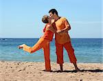 Couple in orange clothes kissing on the beach