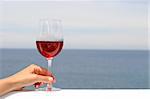 glass of rose wine with the ocean in the background
