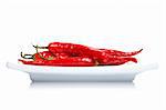 Red hot chili peppers in the dish, reflected on white background with shallow DOF