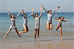 Five teenage girls jumping on the beach