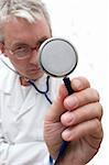 pensive doctor in glasses listening the stethoscope. Soft-focused, focal point is on the stethoscope