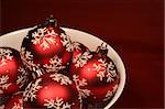 A bunch of red xmas baubles sitting in a bowl.