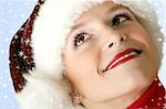 winter portrait of a young smiling woman with a christmas cap and snowflakes