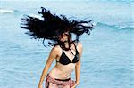 Young bikini girl waving her hair against beach waves