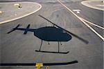 Aerial of helicopter shadow on airport runway pavement.
