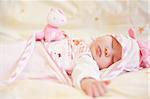 Lying sleeping baby with small teddy bear on bright background