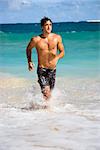 Attractive man running in water on Maui, Hawaii beach.