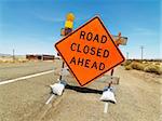 Road sign on rural highway warning that road is closed ahead.